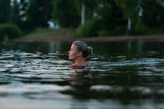 Woman swim in river during peaceful summer evening