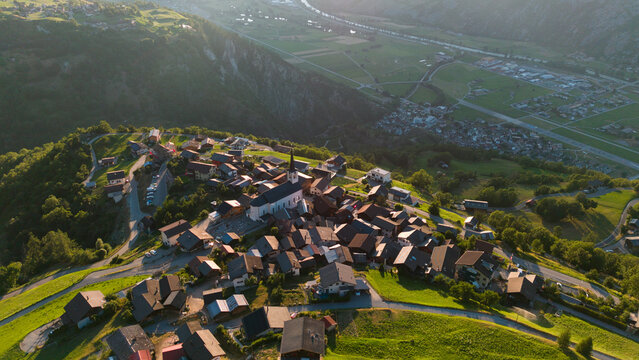 Aerial drone landscape of Ergisch alpine village in Switzerland, featuring the iconic church steeple, traditional roofs, and scenic green mountain valley in the Alps, Ergisch, Wasserfall Turtmann