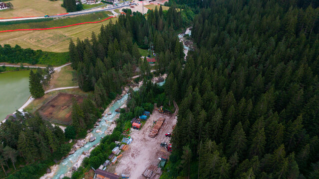 aerial view of a village with river and buildings in neutral calm setting from above with concrete, wood, and metal materials and green, brown, blue, and red colors.