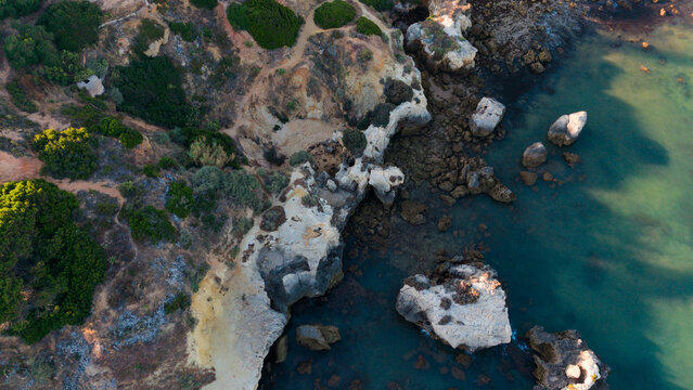 serene rock formations in a coastal landscape viewed from above with lush vegetation and clear water under a soft blue sky, nature photography and travel imagery.