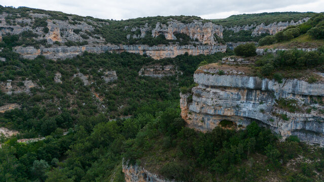 serene cliffs and forest in a majestic natural landscape viewed from above, with vibrant green and gray tones and a road cutting through the scene, nature photography and scenic.