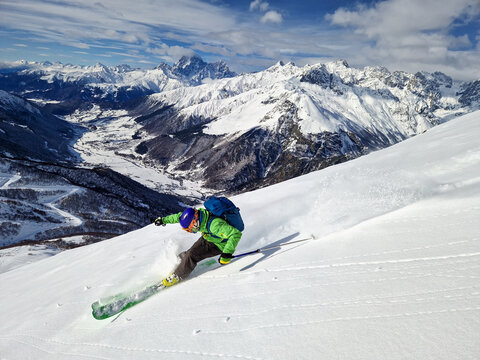 Skier carving through powder on alpine mountain slope