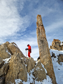 Skier in red outfit beside snowy mountain rock spire