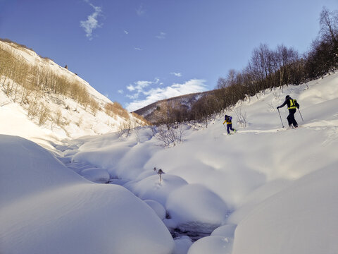 Ski tourers cross deep powder in snowy mountain valley