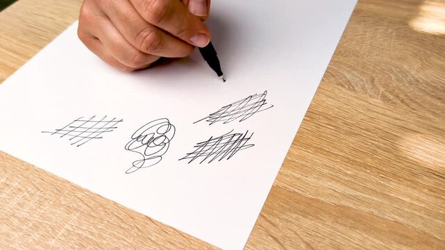 Close-up of a hand drawing spontaneous doodles on white paper with a pen, suggesting thoughts, emotions and inner expression during a conversation or creative process.