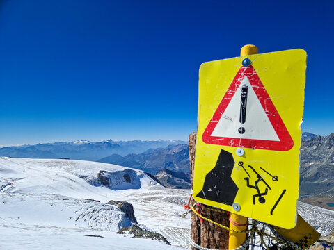 Avalanche warning sign above snowy alpine mountain landscape