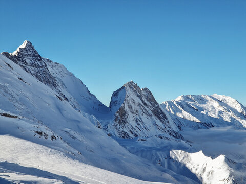 Snow-covered alpine peaks beneath clear winter sky