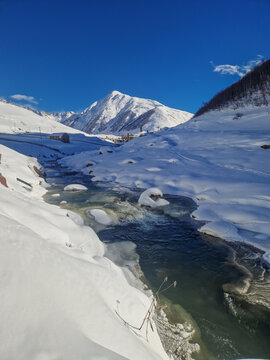 Snowy mountain stream beneath clear blue winter sky