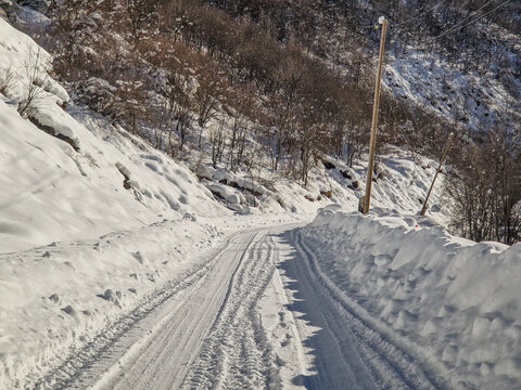 Snow-covered mountain road winding through a winter forest
