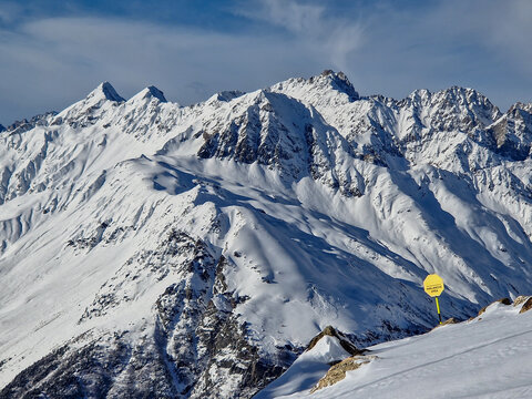 Snow-covered mountain range with warning signal in winter