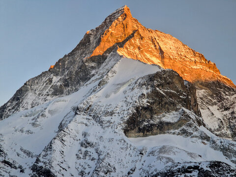 Sunlit snow-covered mountain peak in winter landscape
