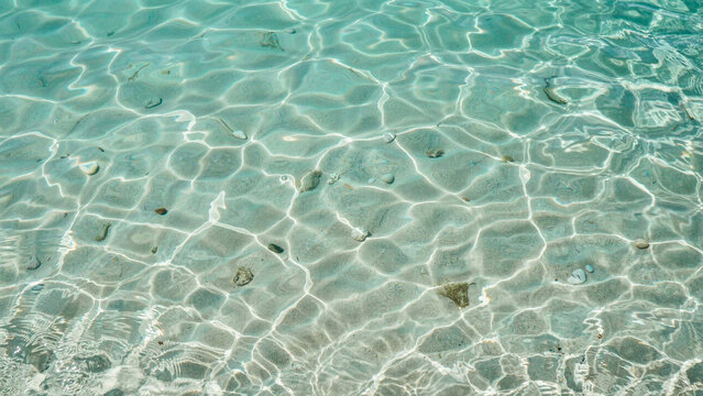 Clear turquoise sea water surface with sun light caustic patterns shimmering on the sandy seabed turquoise caustics sunlight transparent tropical vacation abstract