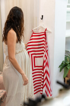 Pregnant woman choose striped dress during clothing shopping