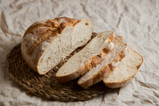 Rustic artisan bread loaf with slices on rattan base