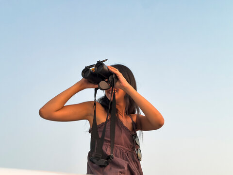 Woman use binoculars against clear sky