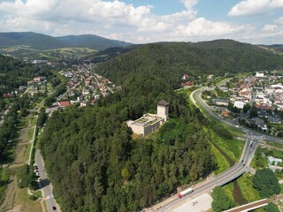 Muszyna - Polska Pięknie położone miasto w górach Beskidach zdjęcia wykonane dronem z powietrza. Zamek na wzgórzu, las, niebo, chmury, miasteczko, dolina, rzeka, lato, wiosna. © Konrad