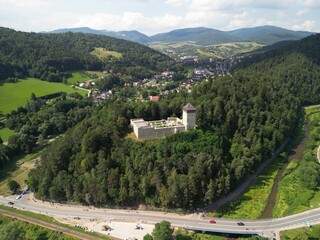 Muszyna - Polska Pięknie położone miasto w górach Beskidach zdjęcia wykonane dronem z powietrza. Zamek na wzgórzu, las, niebo, chmury, miasteczko, dolina, rzeka, lato, wiosna. © Konrad