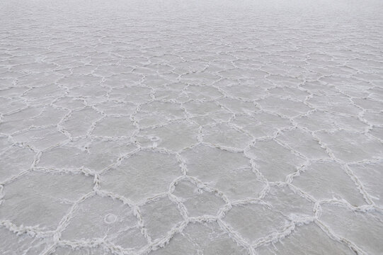Vast expanse of grayish-white salt flat formations, aerial view.