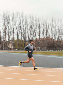 Male athlete run on outdoor track during overcast day