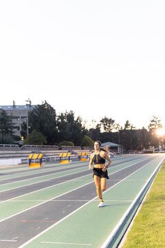 Woman run on outdoor track at sunset