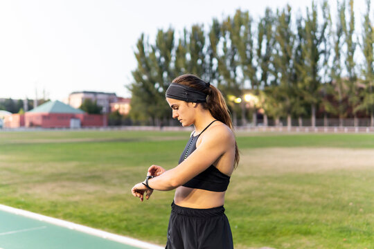 Female runner check smartwatch on outdoor athletics track