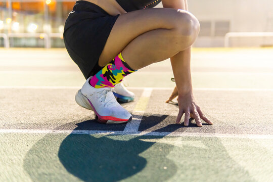 Woman runner poised at starting line on athletics track