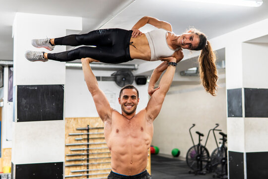Fit couple perform acrobatic strength exercise in gym