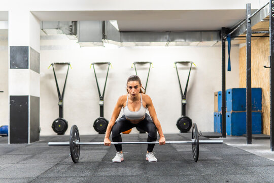 Female athlete prepare to lift barbell in gym