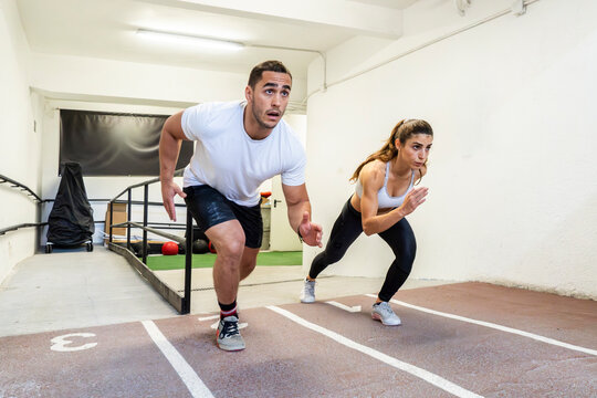 Athletic couple sprinting from starting line in gym