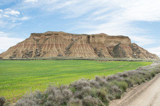 Agriculture and an eroding hill with avalanching parts on its slopes, semi-desert Bardenas Reales, Spain