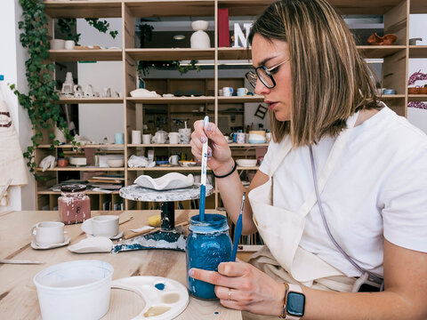 Woman ceramic artist mixes blue glaze in pottery studio