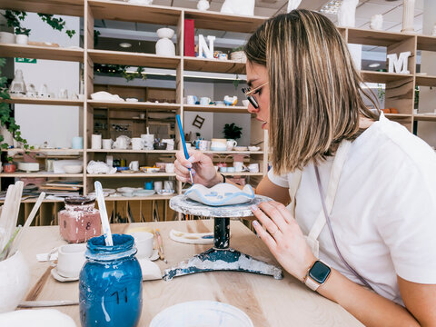 Woman paint handmade ceramic plate in pottery workshop