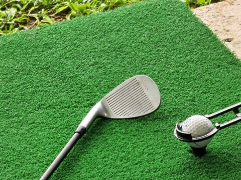 Golf Wedge Club and Teed Ball on Green Driving Range Mat