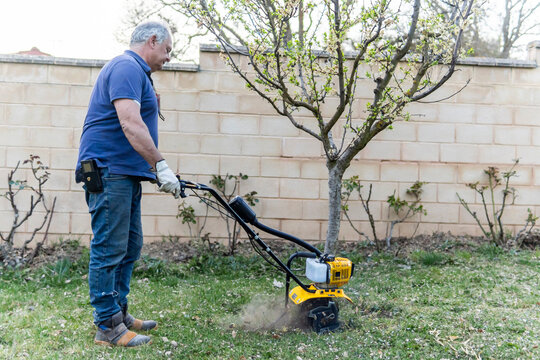 Man uses motorized tiller to prepare garden soil