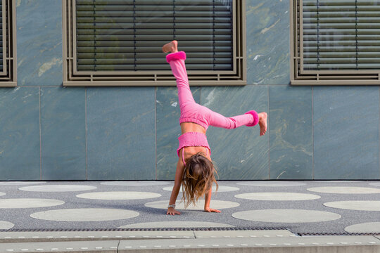 Child perform handstand on urban sidewalk in summer