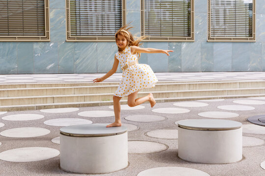 Girl jump on platform in city during summer playtime