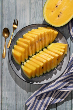Sliced yellow watermelon on plate with gold cutlery