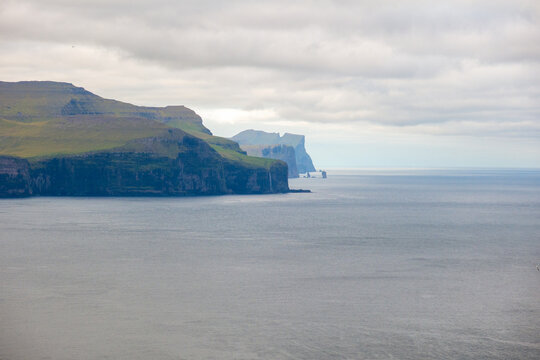 Eysturoy Island cliffs and Risin og Kellingin emerging from the Atlantic Ocean in background