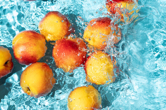 Fresh nectarine splash in turquoise swimming pool water