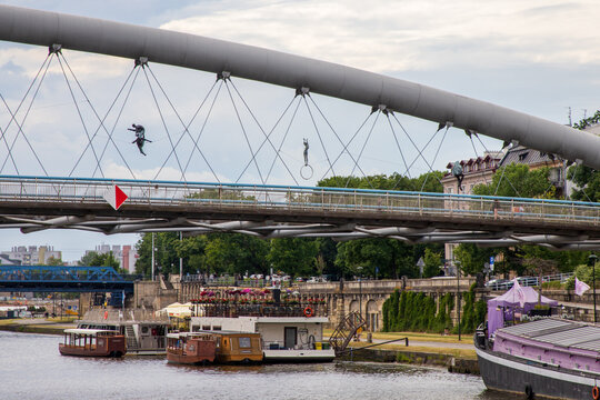 Balancing acrobatic sculptures suspended above the Vistula River on Father Bernatek Footbridge. Created by Polish sculptor Jerzy Kędziora. Suspended across the bridge. Krakow, Poland, June 9, 2026. 