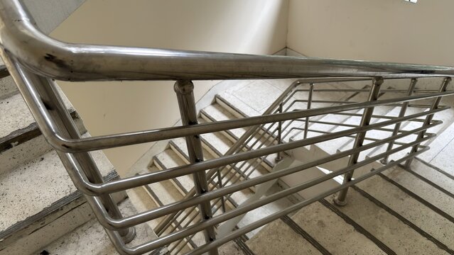 Looking down a modern concrete staircase with a sleek metal railing
