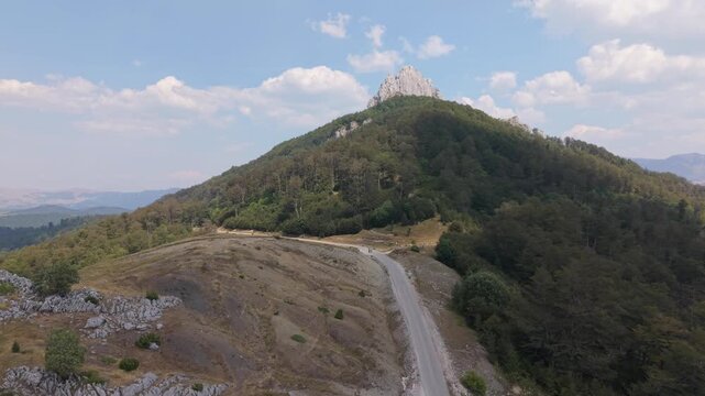 Aerial Drone Flying Along Mountain Road Towards Rocky Peak Visocica