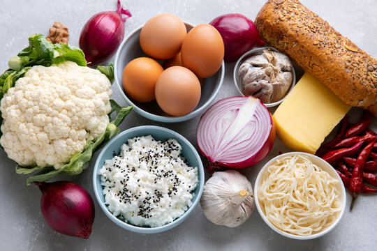 Assorted healthy ingredients including cauliflower eggs red onions garlic cheese bread