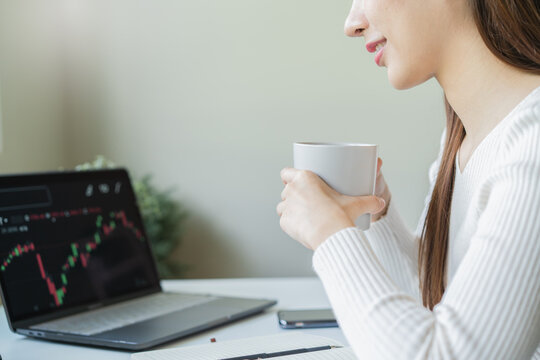 Financial investment in exchange stock concept, Young woman investor looking at laptop monitor to research the stock market on the digital marketplace platform at home.