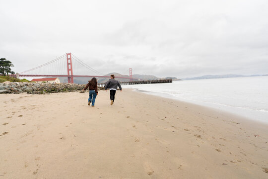 couple running frolicking together beach san francisco golden gate