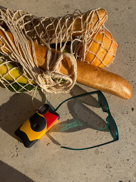 Mesh bag with groceries, disposable camera and sunglasses