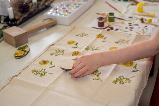 small child stamps a print on fabric with paints