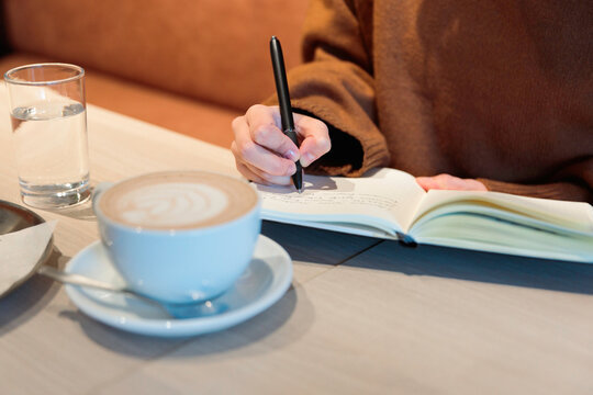 Woman writing in journal at cafe