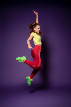 Woman dancer jump in colorful fitness outfit in studio