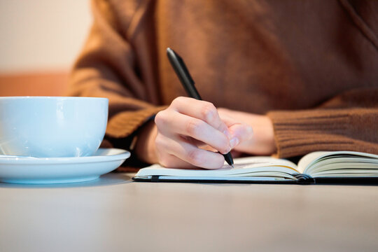 Woman writing in notebook at cafe